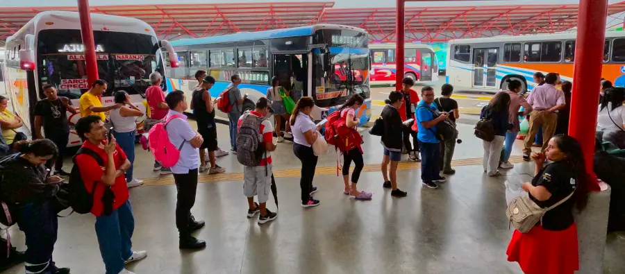 Personas esperando en fila para tomar el autobús a Carrillos de Poás.